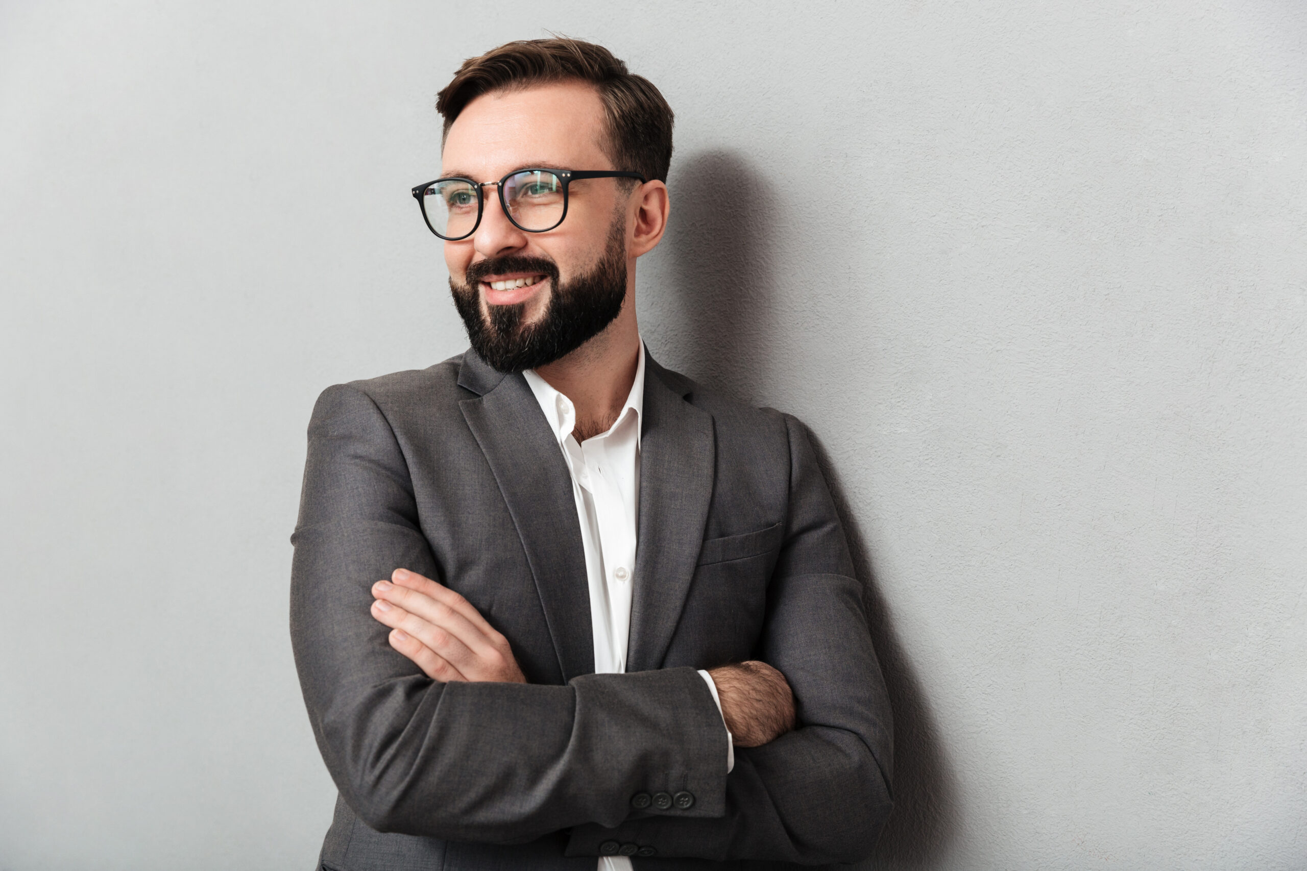 close up portrait pleased unshaved man eyeglasses looking camera with sincere smile standing with arms folded isolated gray scaled