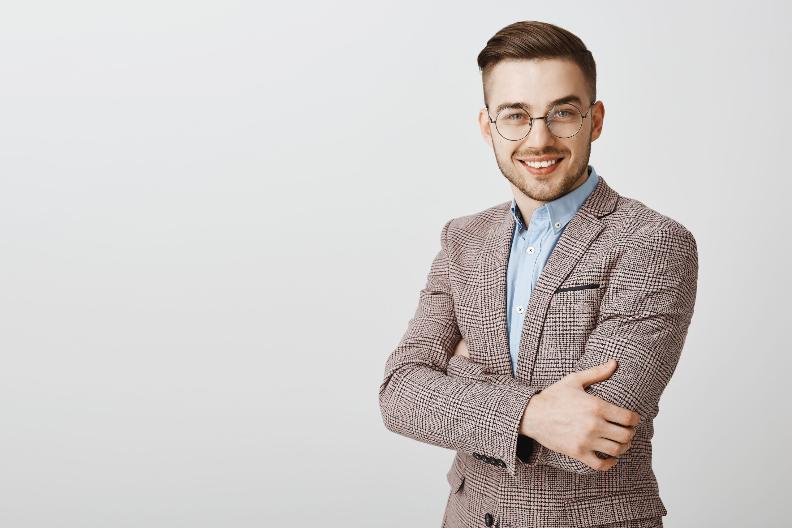 Ambitious smart and intelligent good-looking european male entrepreneur in glasses and stylish jacket crossing hands on chest and smiling in self-assured smile assuring his company best. Copy space